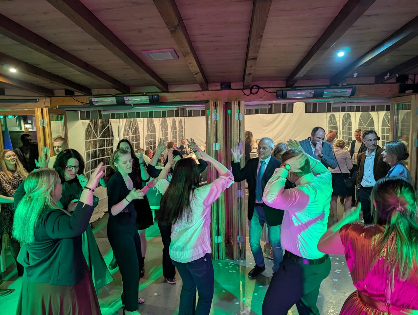 Hochzeitsfeier in der schwarzenauer Mühle Menschen tanzen und feiern in einem festlichen Veranstaltungsraum mit bunten Lichtern.