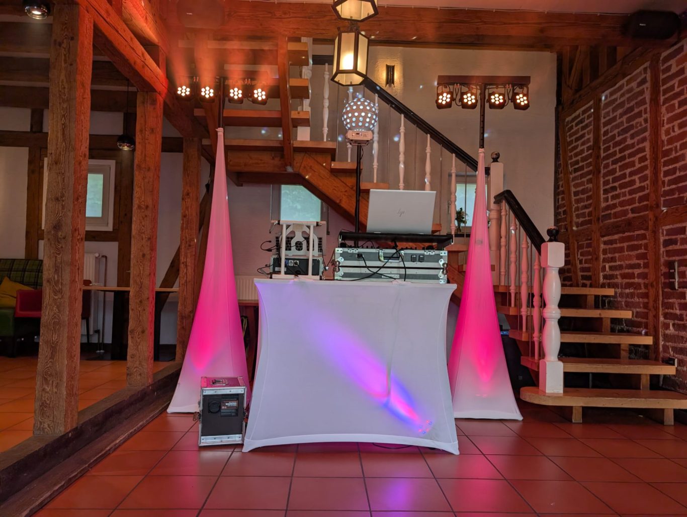 Hochzeitsfeier in der Remise Haichen Tanzfläche mit DJ-Setup, beleuchtet von rosa und lilafarbenen Lichtern.