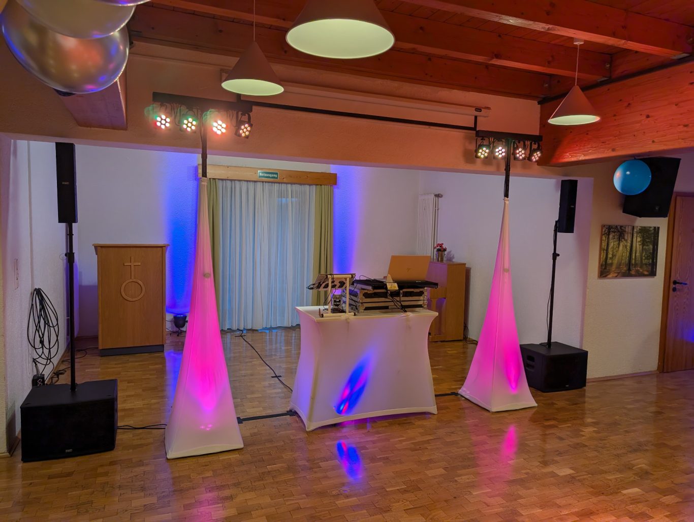 80er Mottoparty zum 60. Geburtstag im BK Heim Netphen - Beienbach Dekorierte Veranstaltungsfläche mit DJ-Tisch, Lautsprechern und Beleuchtung in lila und blau.