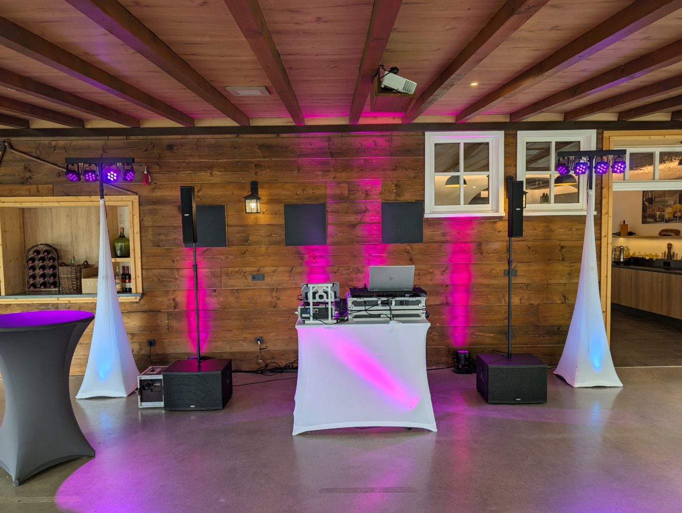 Hochzeitsfeier in der schwarzenauer Mühle DJ-Setup mit Lichtern in Pink und weißen Ständern, Holzdekor im Hintergrund.